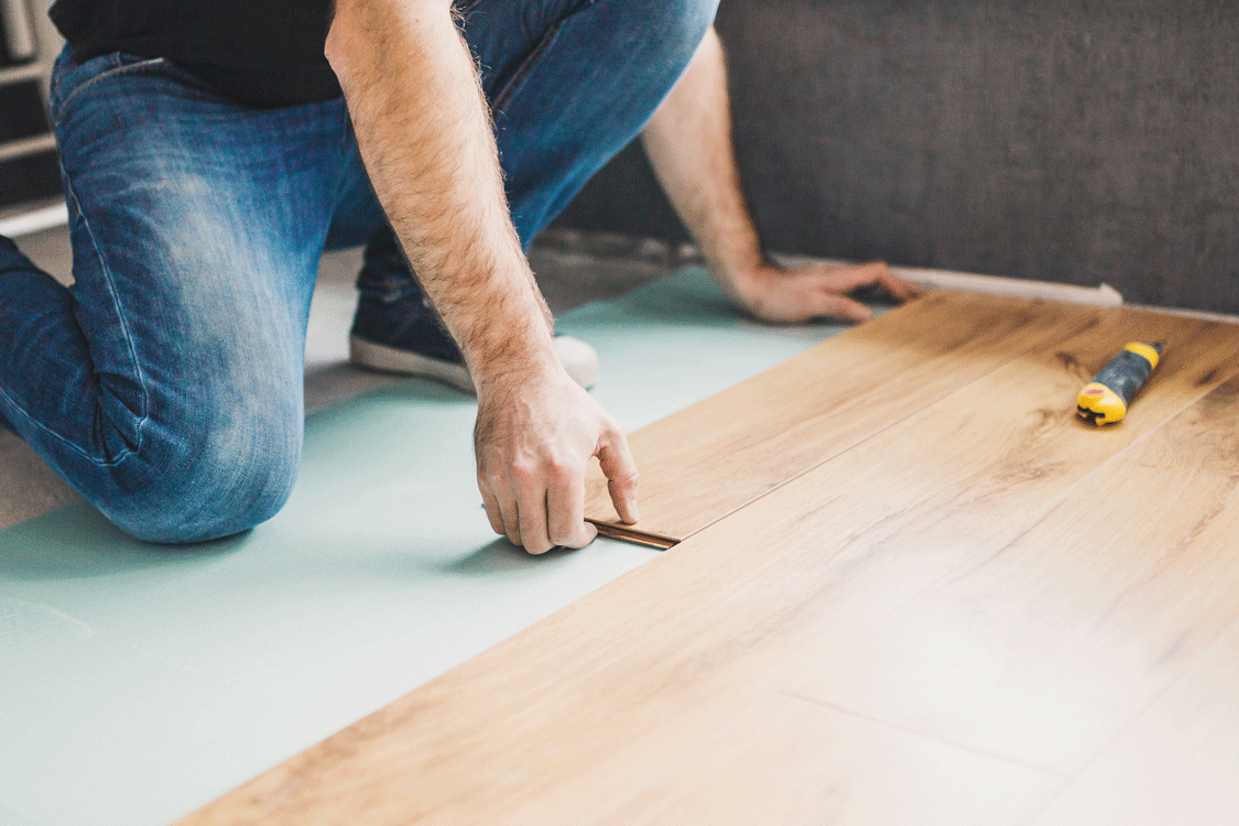 Un artisan pose du parquet dans la future chambre d'un appartement pour le locatif