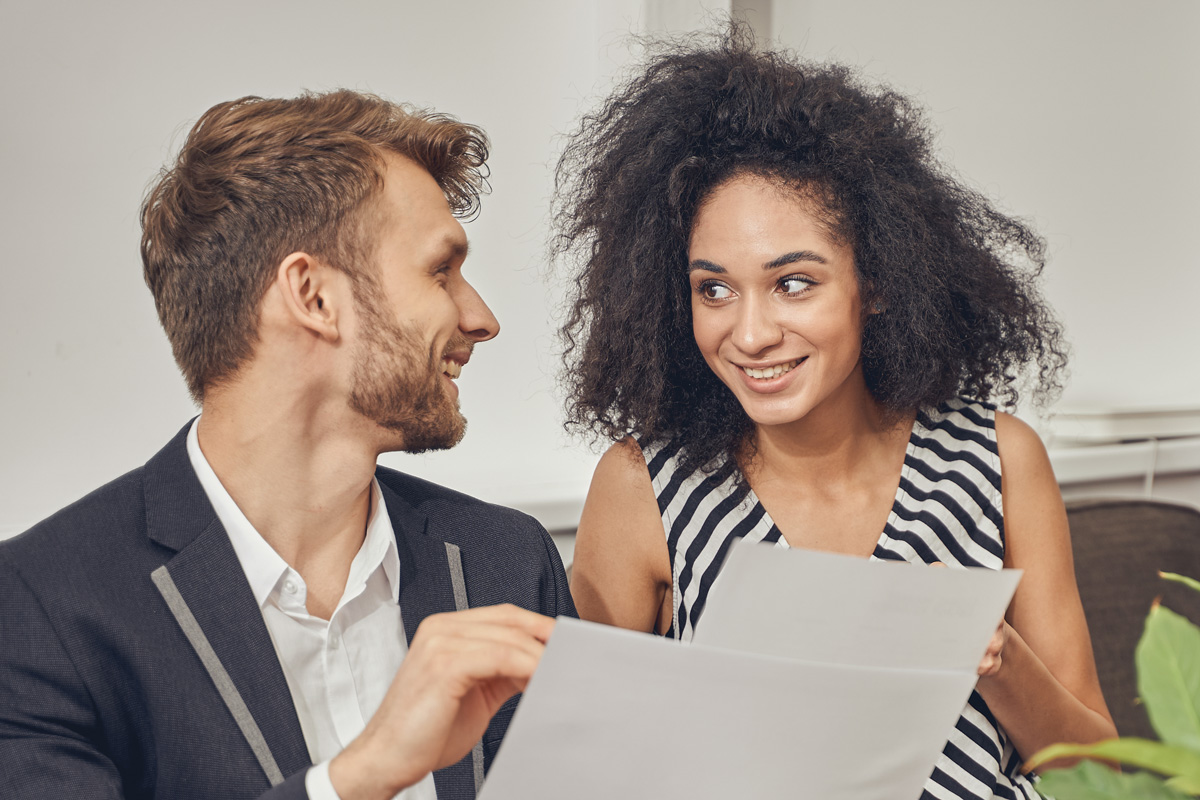 Un jeune couple consulte des documents financiers avant d'acheter un bien immobilier.