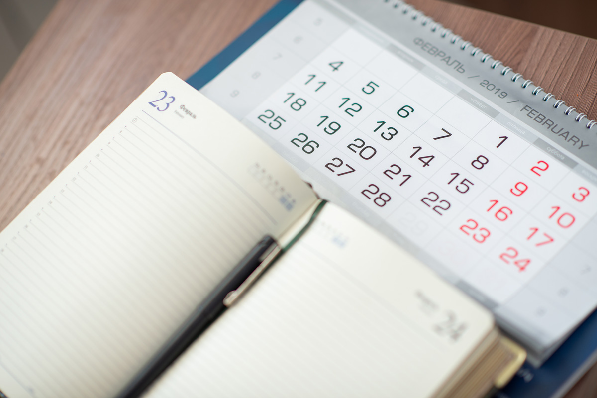 Calendrier et bloc note posés sur une table.