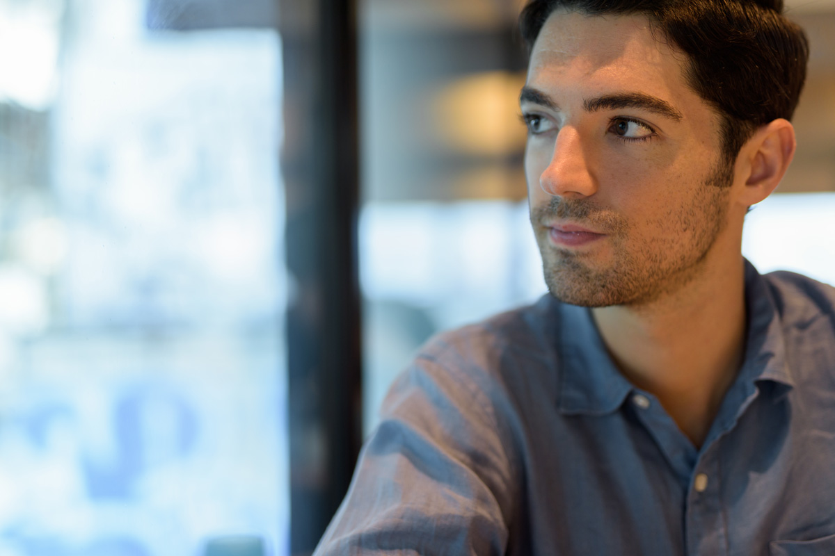 Un homme en chemise bleue regarde l’horizon, symbolisant le doute.