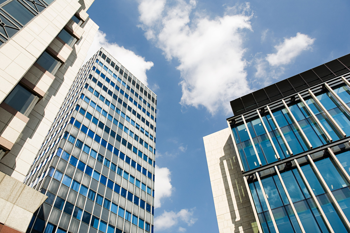 Angle de vue en contre-plongée sur des immeubles de bureaux modernes avec des façades vitrée, symbolisant le secteur d'activité de la finance dans les quartiers d'affaires comme La Défense à Paris.