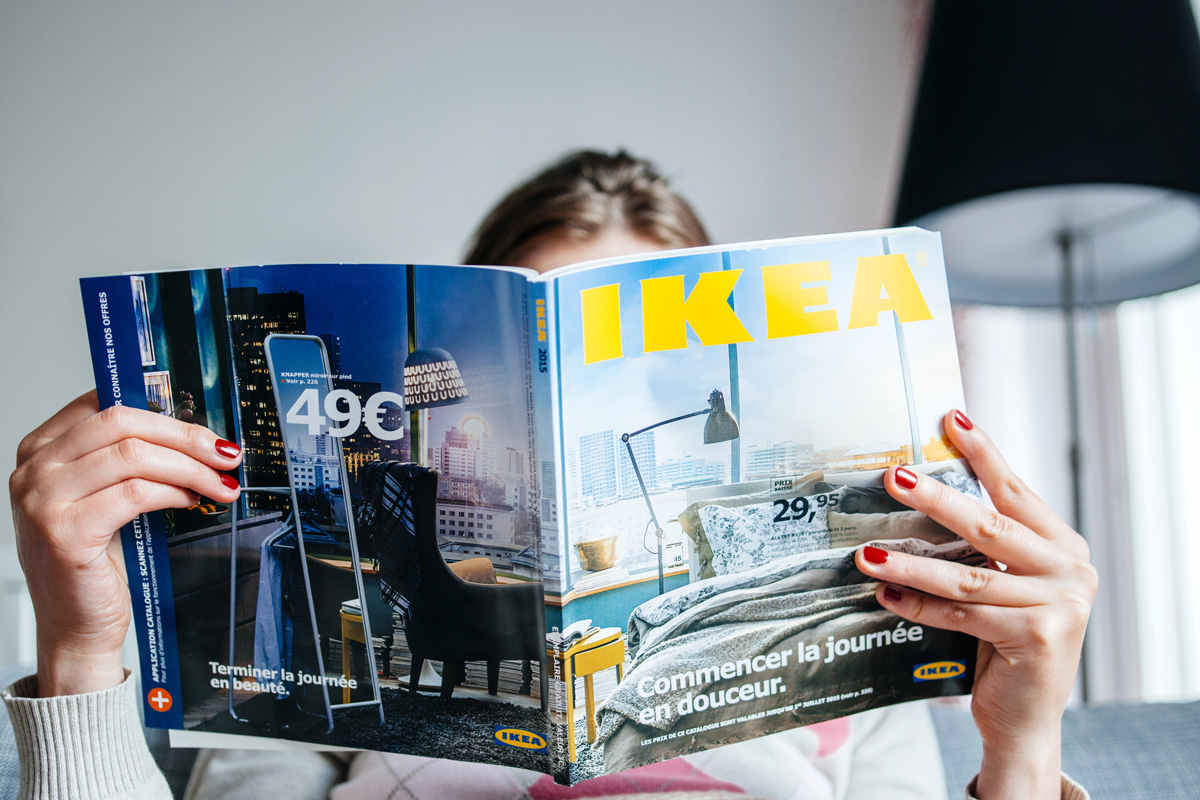 Une femme lit un magazine de la marque de mobilier IKEA