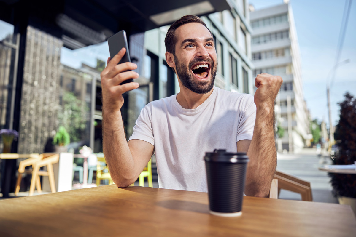 Une homme très heureux lève le poing en l’air en signe de victoire, symbolisant les émotions que l’on peut ressentir dans l’investissement locatif