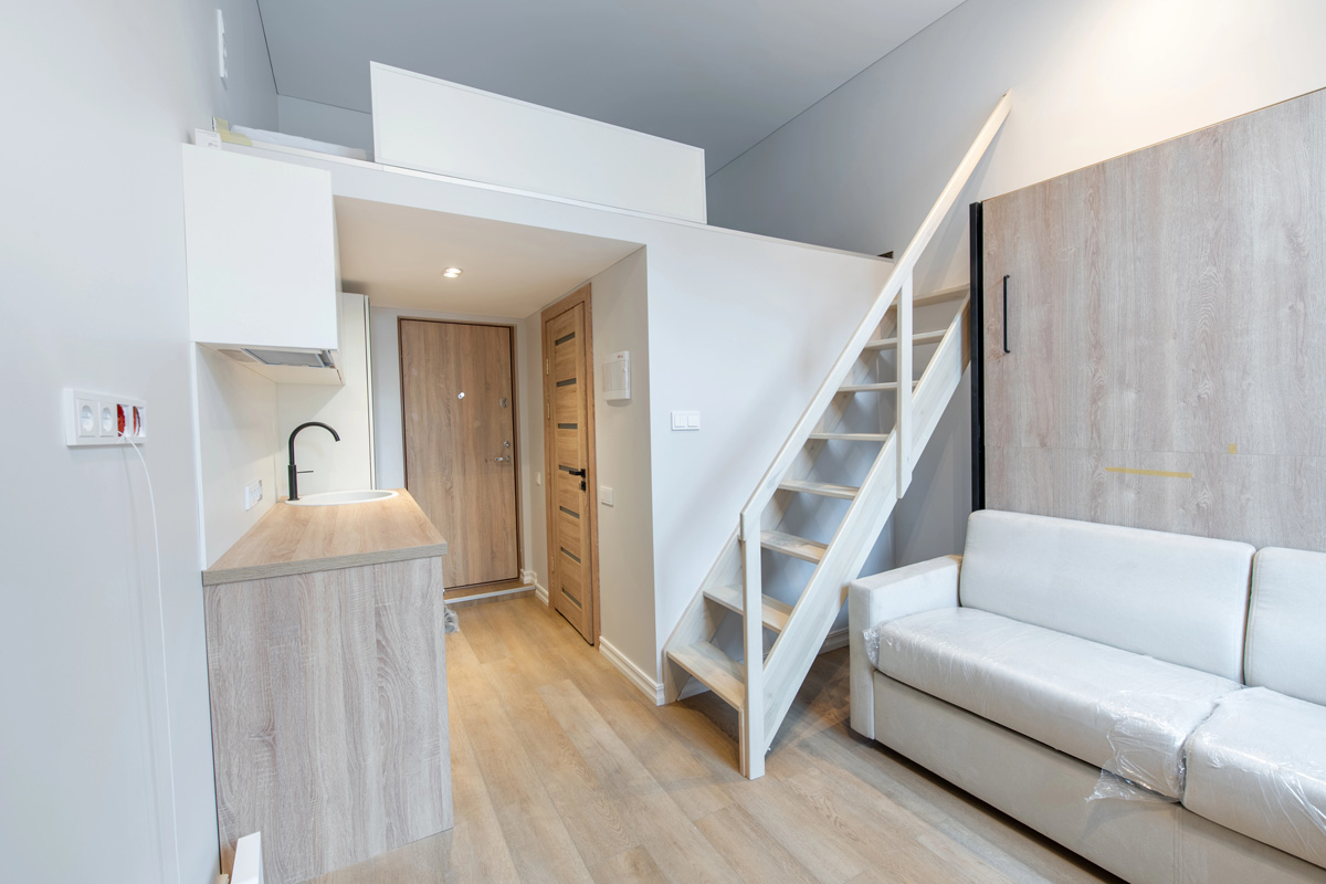 Intérieur d’un petit studio optimisé avec une mezzanine accessible par une échelle au-dessus de la salle d’eau.