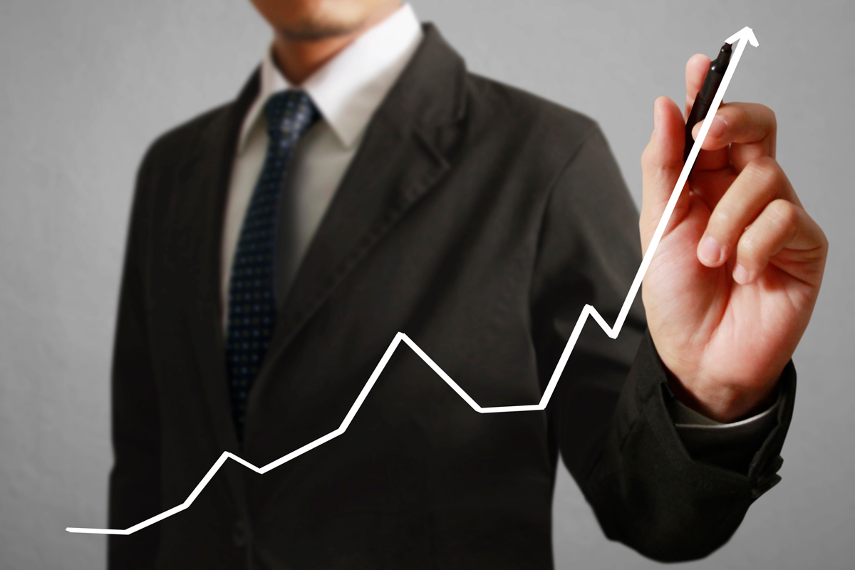 Un homme en costume trace une courbe ascendante symbolisant la valorisation patrimoniale dans l'investissement locatif