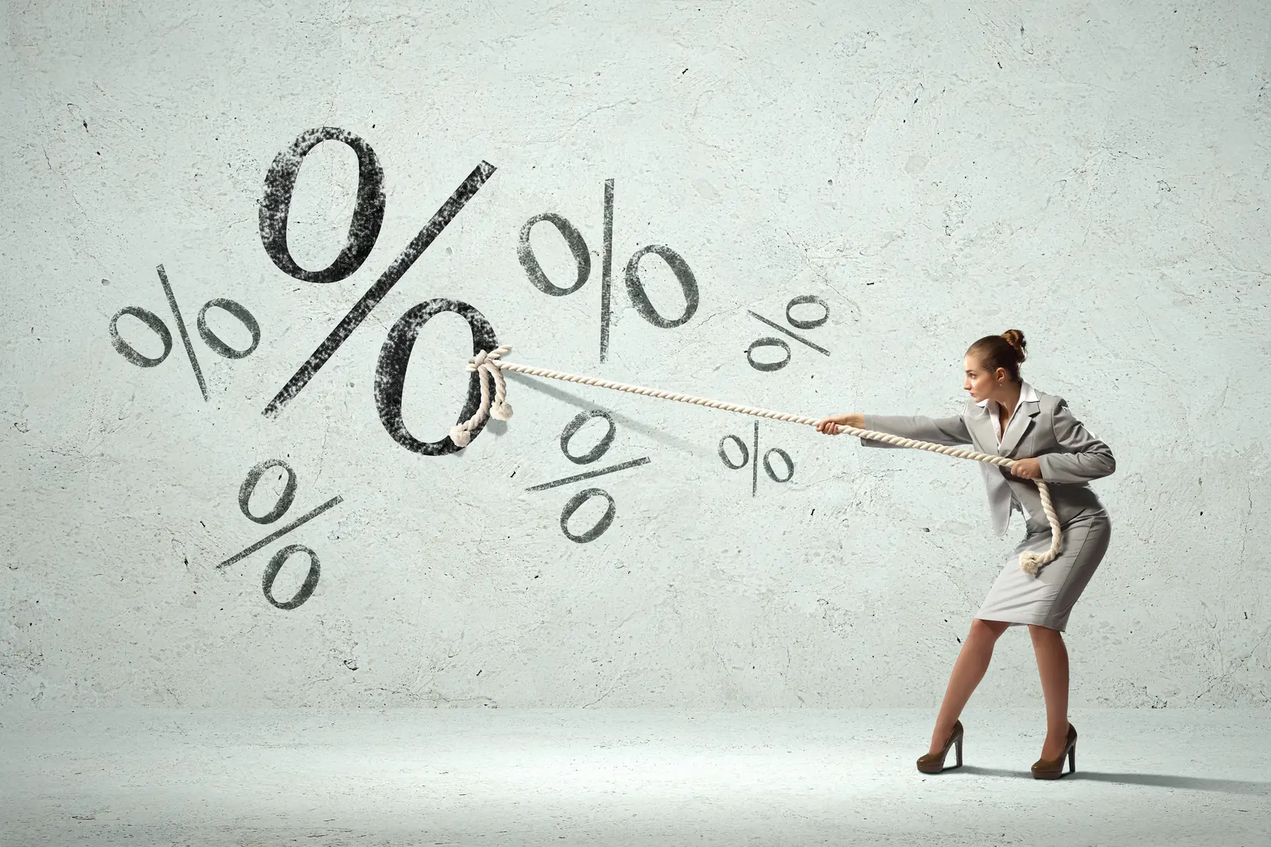 Femme tirant sur un symbole pourcentage à la corde, illustrant la négociation du taux fixe pour investir en meublé en 2026