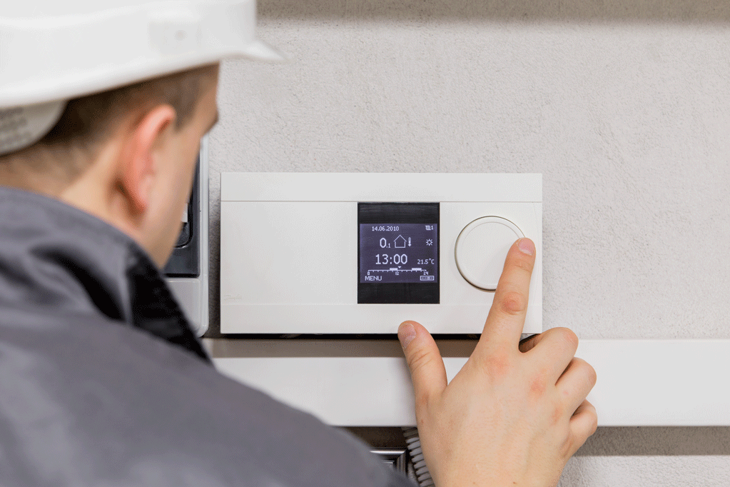 Un chauffagiste configure le thermostat d'un logement