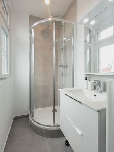 Salle de bain moderne et lumineuse avec une belle cabine de douche arrondie et un meuble vasque