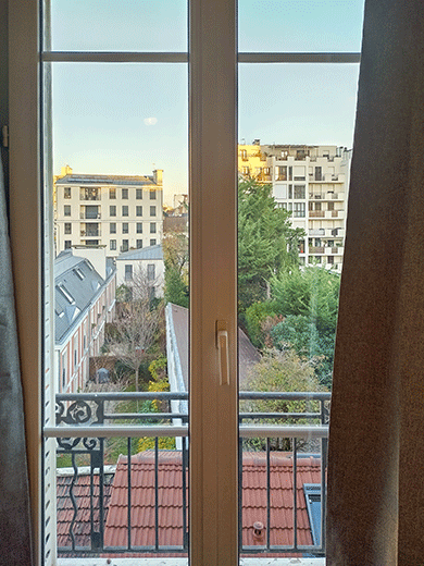 Vue sur la ville de Courbevoie à travers une fenêtre dans l'investissement locatif d'Aimee.