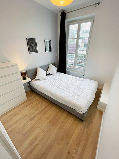Belle chambre meublée lumineuse avec une peinture gris bamako et un parquet flottant clair.