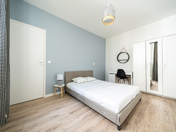 Chambre rénové avec un mur contrastant bleu pastel, un lit gris et du mobilier blanc dans un style scandinave