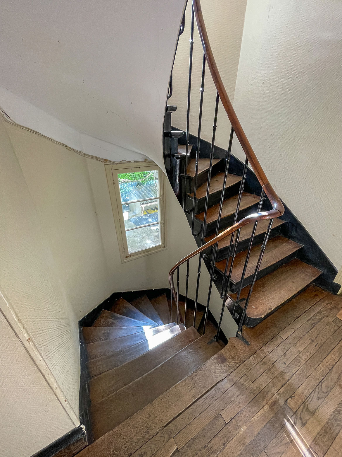 Escalier en bois traditionnel des années 1930. Les murs sont peints en beige. Le tout est très propre.