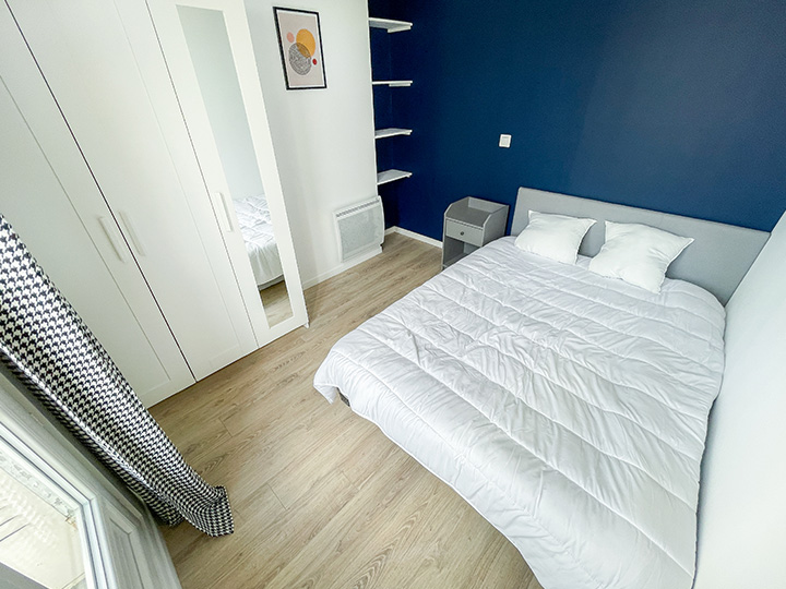 Chambre rénové par ImAvenir avec un mur bleu roy contrastant derrière la tête de lit