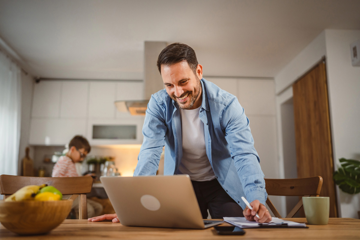 Un homme travaille sur son ordinateur portable dans sa cuisine.