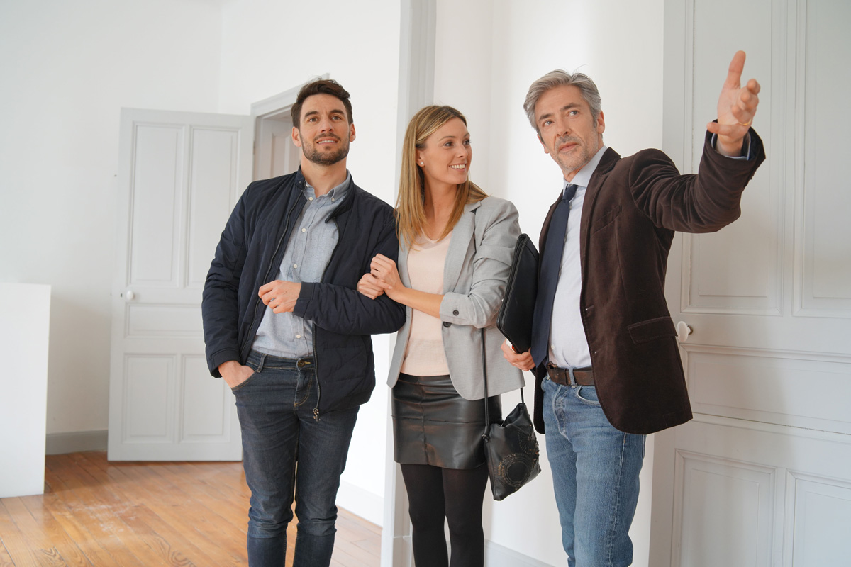 Un agent immobilier fait visiter un appartement à un couple d'acheteurs.