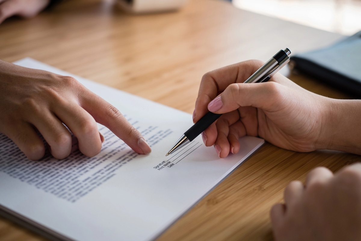 Deux personnes signent un document sur une table