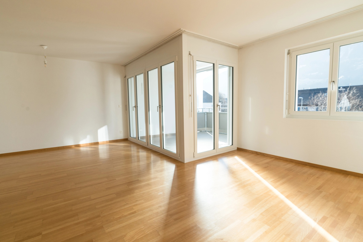 Le bail de location non meublée : Règles, obligations et erreurs à éviter alt : appartement vide avec des murs peints en blanc et beau parquet flottant.