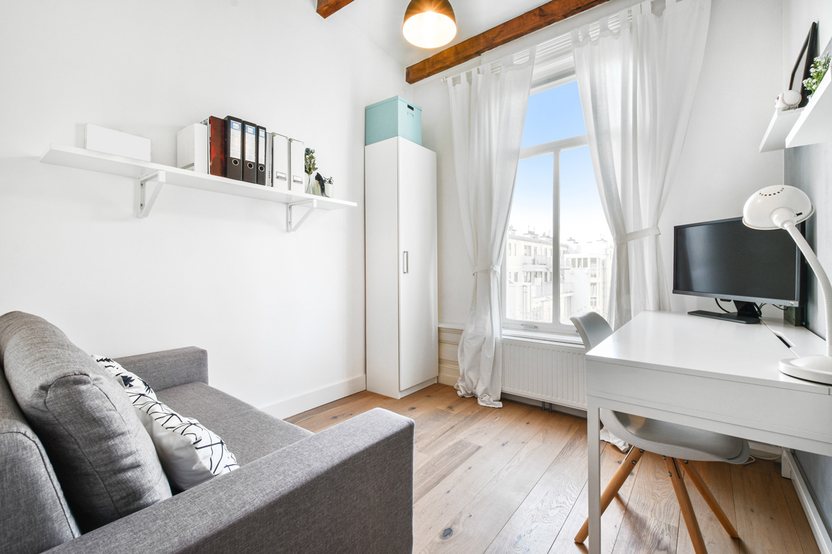 Petit studio meublé pour un étudiant avec une canapé dépliable et un bureau d’études.