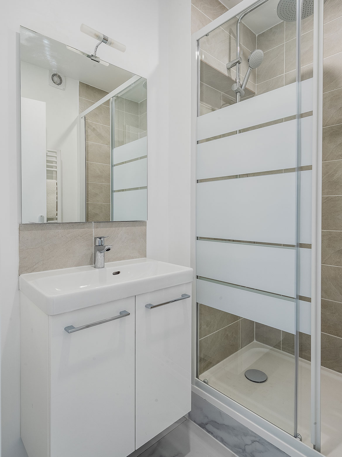 Salle de bain rénové avec un meuble vasque et une cabine de douche avec une paroi vitrée